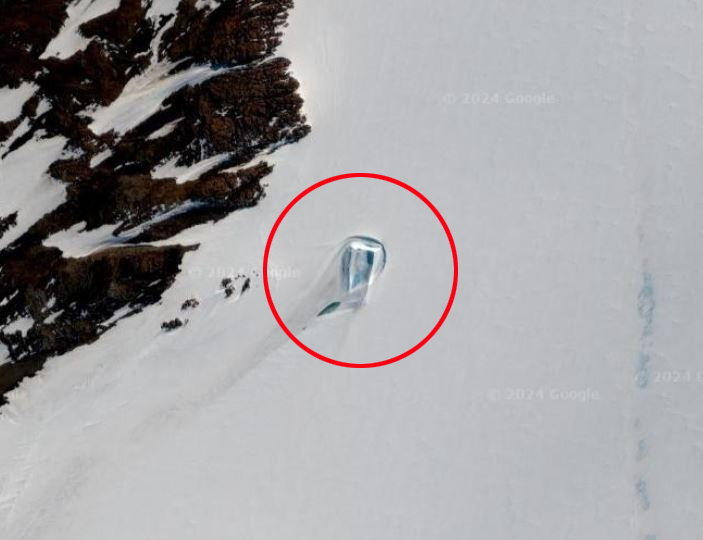 Rectangular shape resembling a dirty doorway in the snowy landscape of Antarctica, circled in red